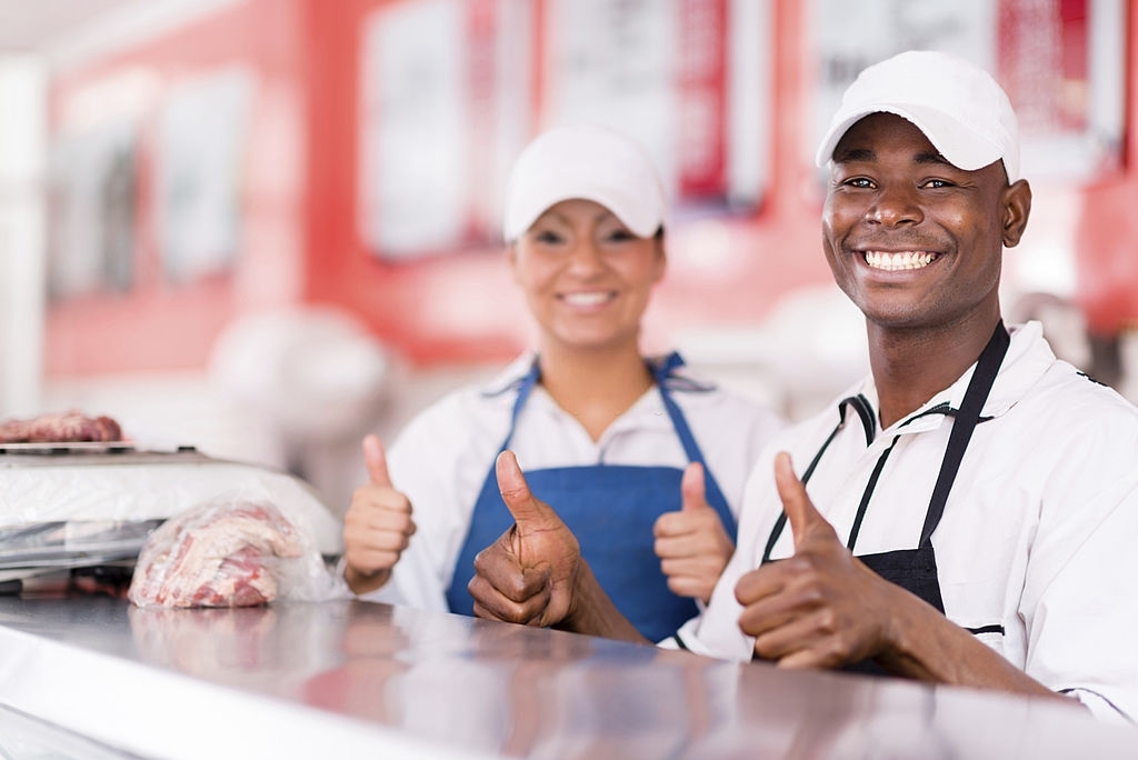 Portrait of a happy couple owning a butchers shop